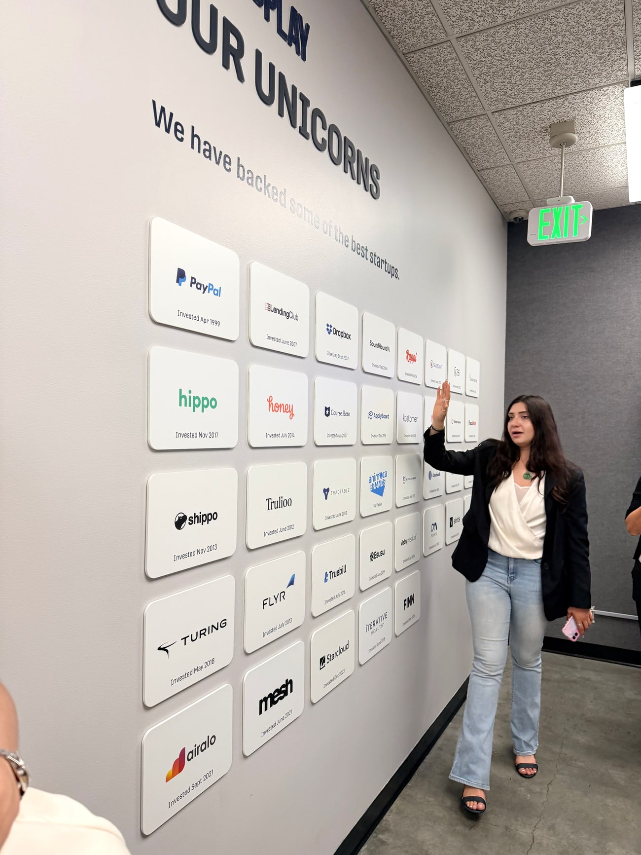 Parede de unicórnios do Plug and Play com placas de PayPal, LendingClub, Dropbox, SoundHound AI, Rappi, Hippo, Honey, Course Hero, Turing, Airalo e outras empresas com a data de cada investimento