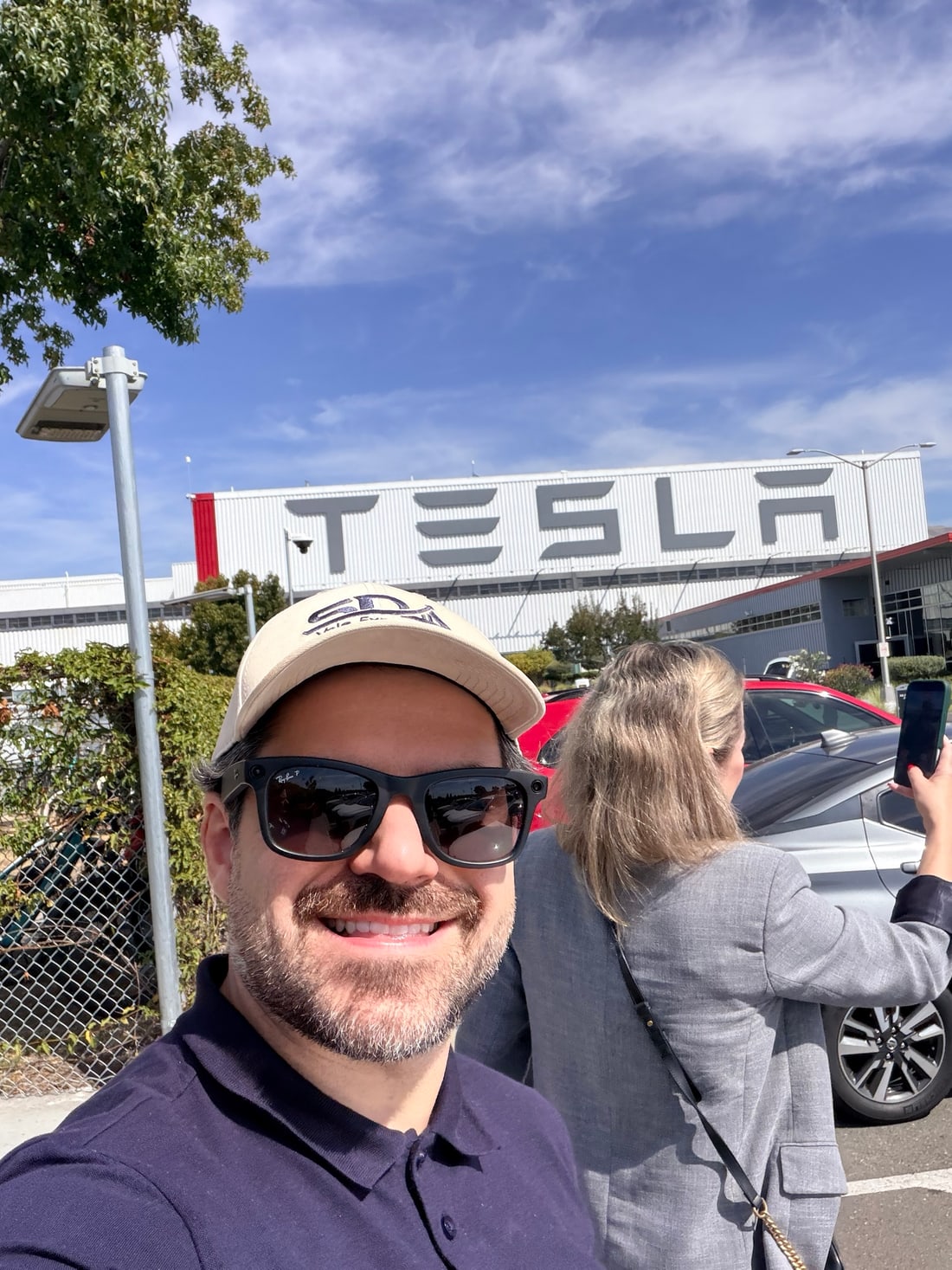Samuel Pereira em frente ao letreiro gigante da Tesla na fachada da fábrica de Fremont, na Califórnia